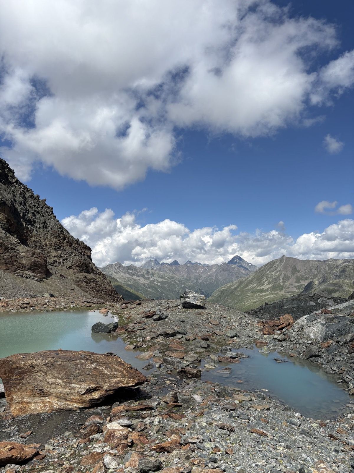 Rocky high-alpine terrain and a turquoise meltwater pool near Schwarzhornfurgga