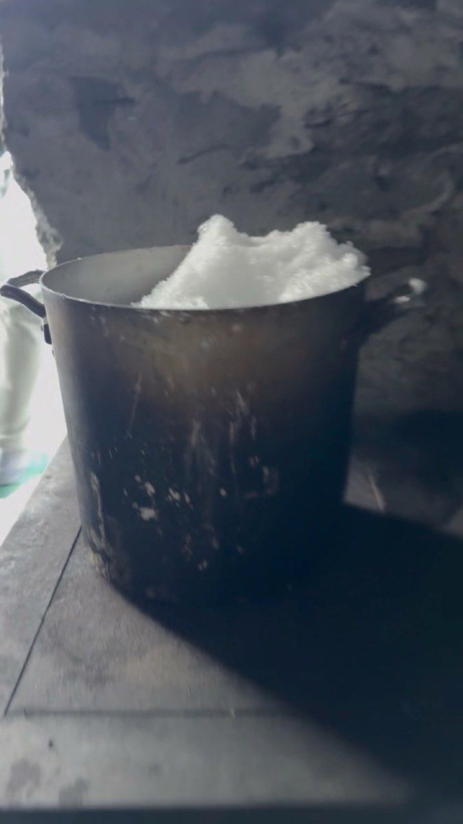 A pot filled with snow inside an unstaffed hut