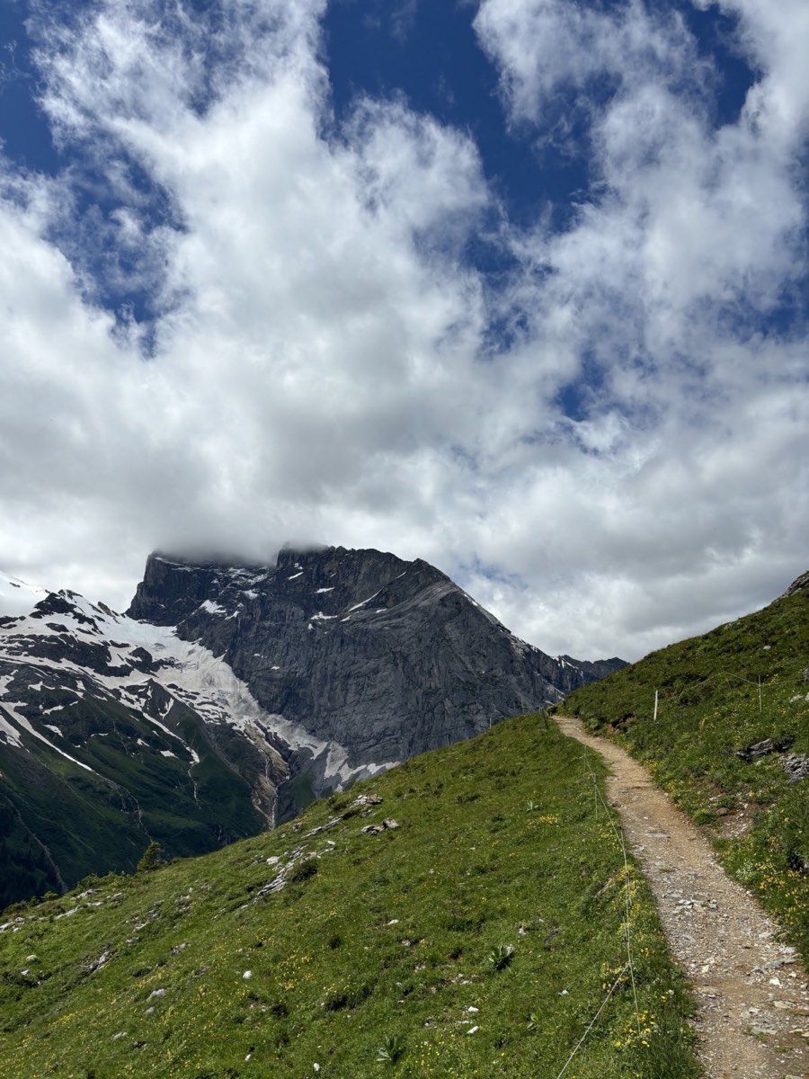 A narrow mountain path beneath a dramatic rock wall near Fürenalp